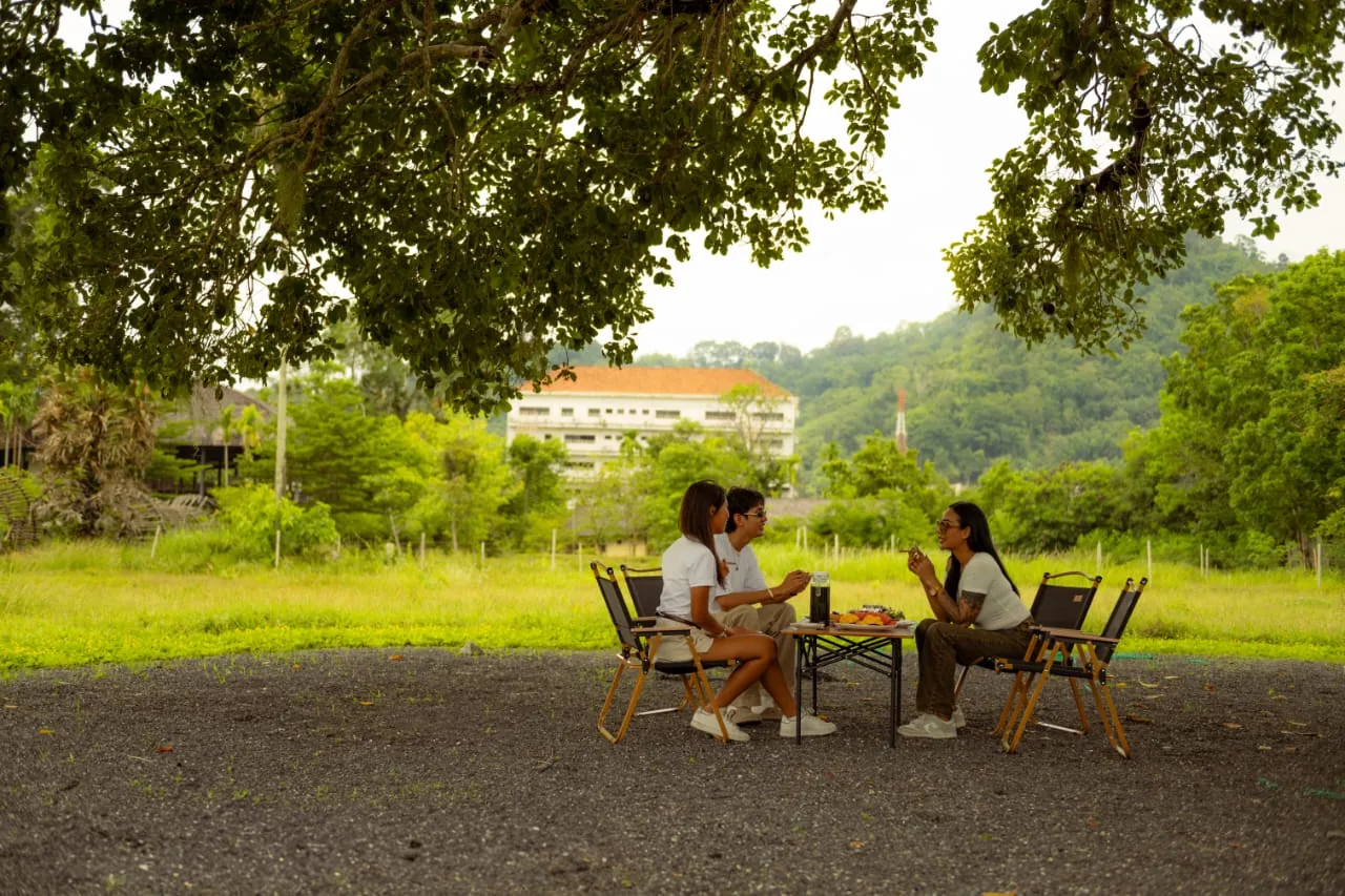 Outdoor dining at a Phuket hillside farm, daytime, greenery in the background