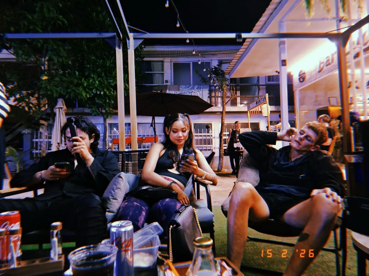 Friends chilling at an outdoor Bangkok bar at night  -  the social scene where cannabis experiences happen