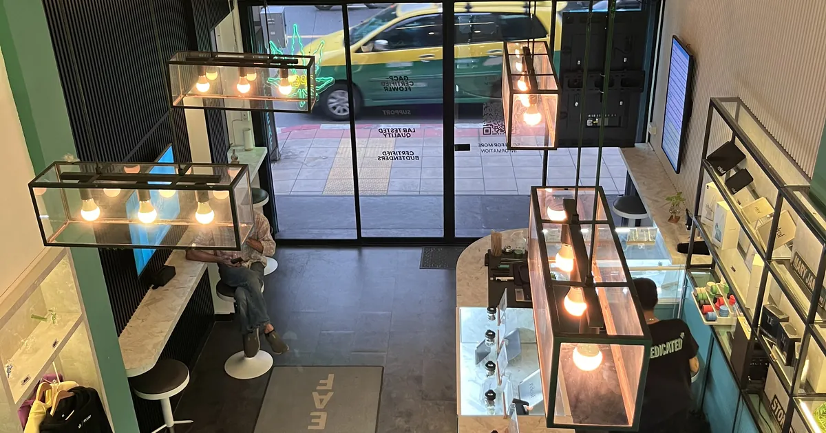 Overhead view of a licensed dispensary shop floor with glass cases and pendant lights above the counter