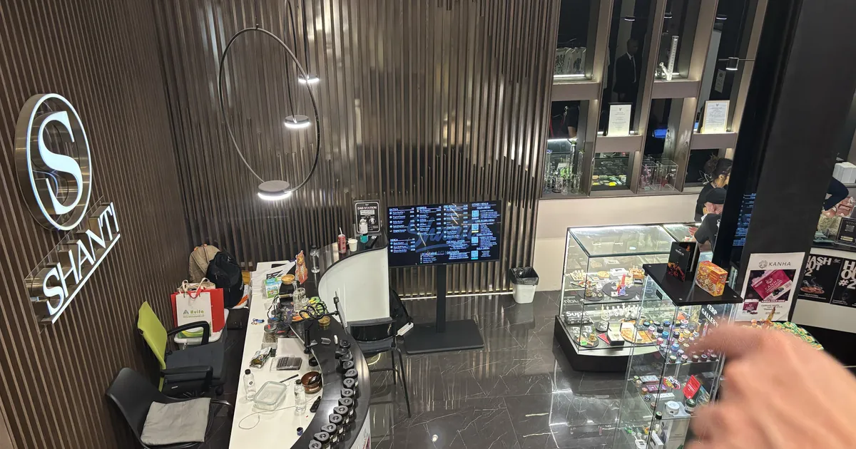Dark wood paneled dispensary lobby with a curved reception desk, a glass display case and a large logo