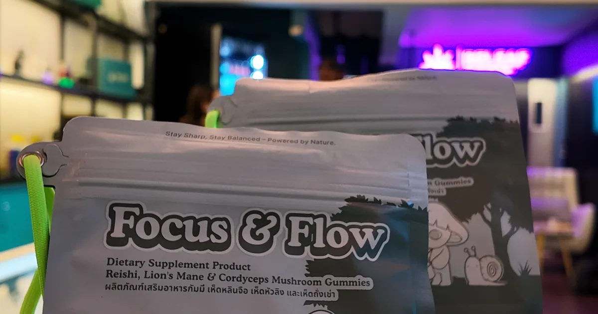 Two pouches labelled Focus & Flow held up in a shop lit with purple neon