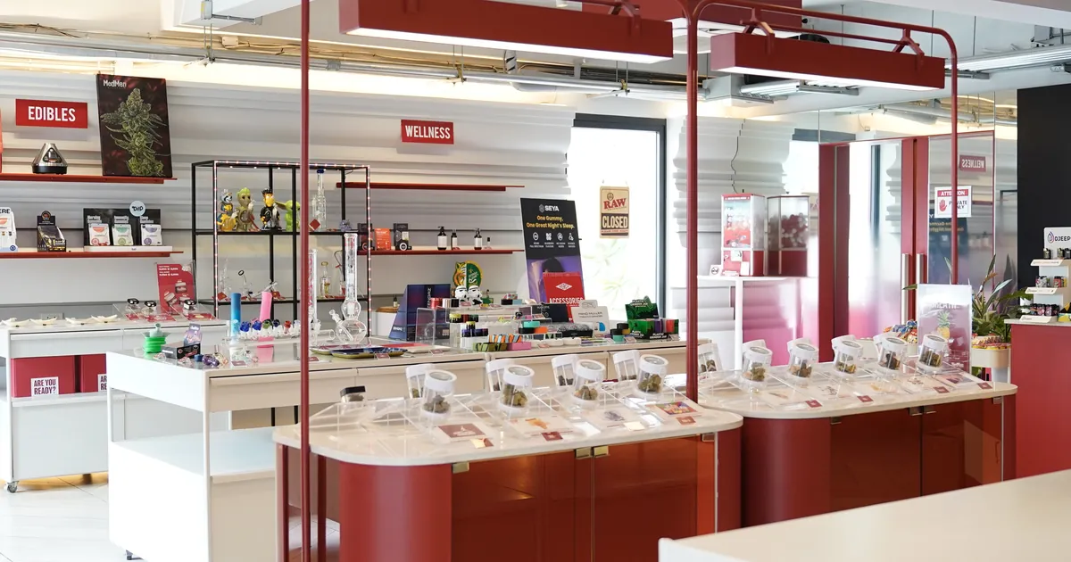 Bright shop with white counters, display jars of flower and shelves under EDIBLES and WELLNESS signs